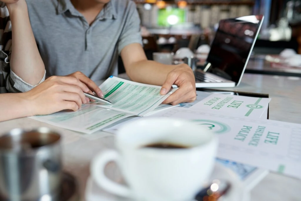 Neldal Insurance - Two people sitting at a table with papers and a cup of coffee.