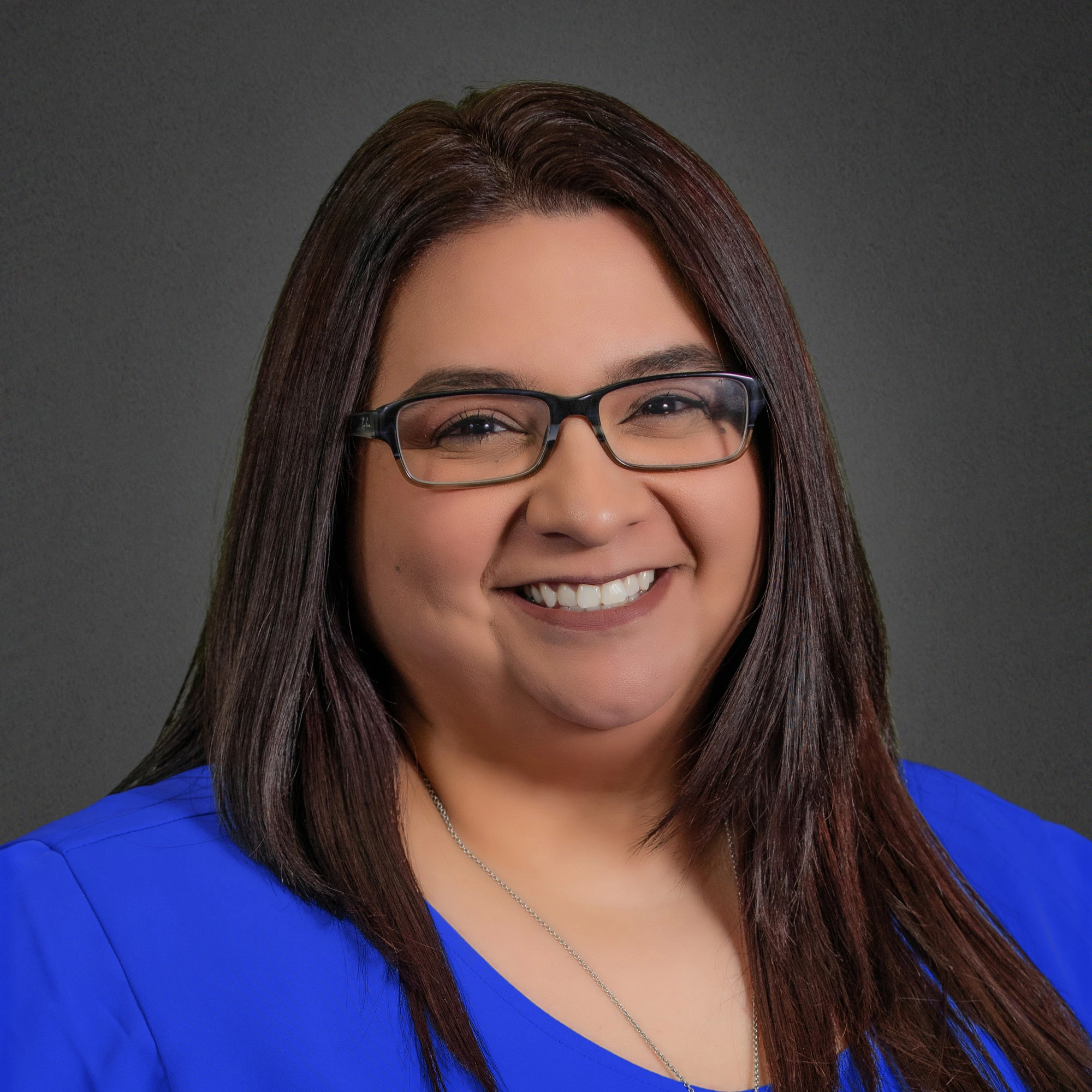 Neldal Insurance - Karina Sanchez. A smiling woman in glasses wearing a blue shirt.